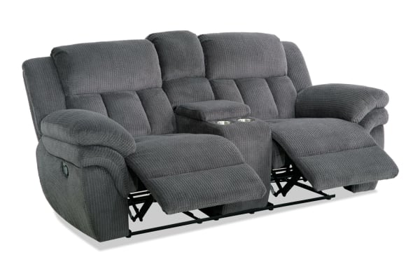 Gray fabric reclining loveseat with plush cushioning, padded armrests, and center console with cup holders, designed for living room comfort.