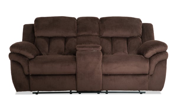 Brown plush fabric reclining loveseat with padded armrests and center console, designed for comfort and relaxation in living rooms.