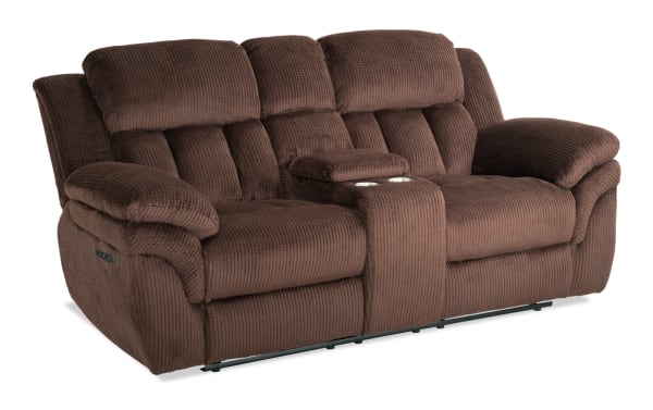 Brown plush fabric reclining loveseat with padded armrests, high back cushions, and a center console with cup holders, designed for comfort and relaxation.