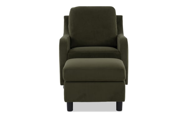 Dark green velvet armchair with matching ottoman, featuring cushioned seat, backrest, and armrests, supported by black wooden legs.