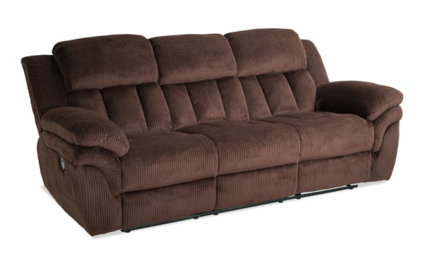 Brown plush fabric reclining sofa with padded armrests and segmented cushioned backrest, designed for living room comfort and relaxation.