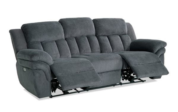 Gray fabric reclining sofa with plush padded armrests and back cushions, featuring two extended footrests for comfort and relaxation.