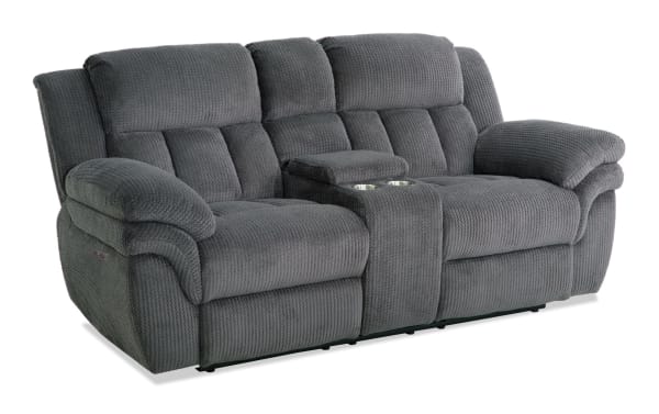 Gray fabric reclining loveseat with plush cushioned armrests, divided backrests, and a center console with cup holders, designed for comfort and relaxation.