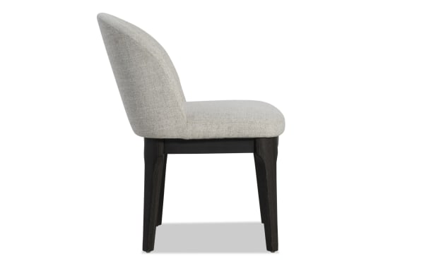 Upholstered dining chair with light gray fabric seat and backrest, supported by dark wood legs, modern minimalist design.