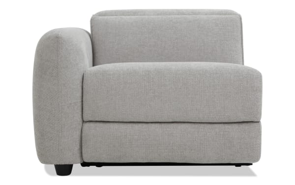 Modern gray fabric armchair with rounded left armrest, cushioned seat and backrest, and black wooden legs, ideal for living room seating.