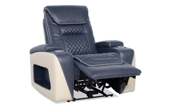 Reclining leather armchair in navy blue and beige with quilted cushioning, padded armrests, cup holders, and a built-in footrest for home theater comfort.