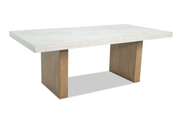 Rectangular dining table with a white concrete top and two wide wooden pedestal legs in a natural finish, modern minimalist style.