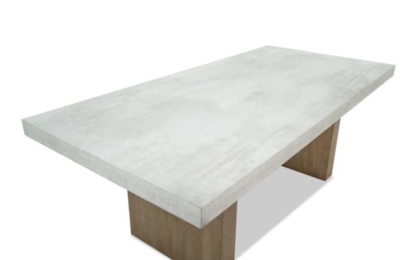 Rectangular dining table with a thick, light gray concrete tabletop and two wide wooden pedestal legs, modern industrial style.