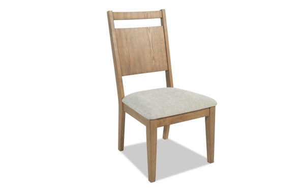 Wooden dining chair with light beige upholstered seat, natural wood finish, straight legs, and a slatted backrest, suitable for modern interiors.