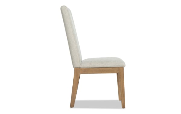 Side view of a modern dining chair with light beige upholstered seat and backrest, supported by natural wood legs and frame.