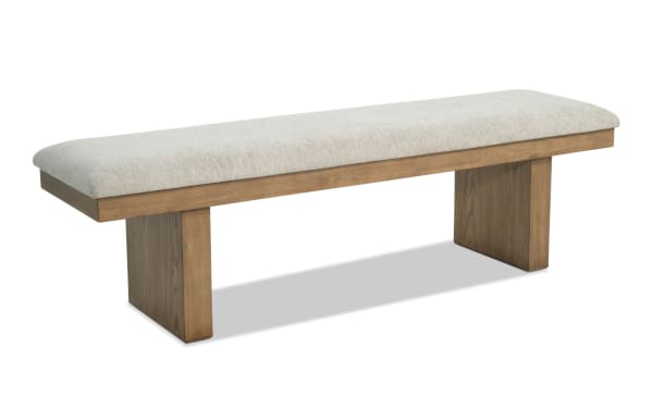 Wooden bench with beige upholstered cushioned seat, featuring a minimalist design with two sturdy rectangular legs, suitable for indoor seating.