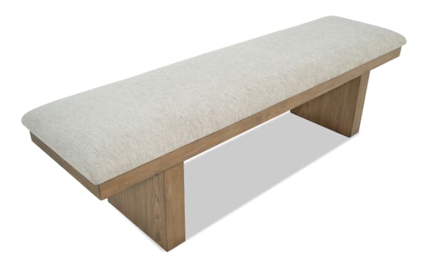 Upholstered bench with light beige fabric seat and wooden base in natural finish, featuring a minimalist modern design for indoor seating.