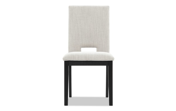 Upholstered dining chair with beige fabric seat and backrest, black wooden legs, and a rectangular cutout at the lower back.