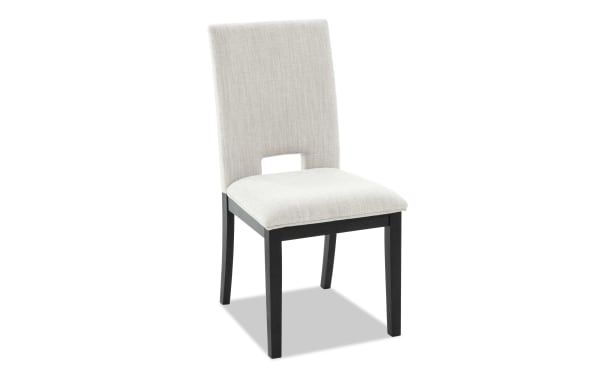 Upholstered dining chair with light beige fabric seat and backrest, black wooden legs, and a modern cutout design on the back.