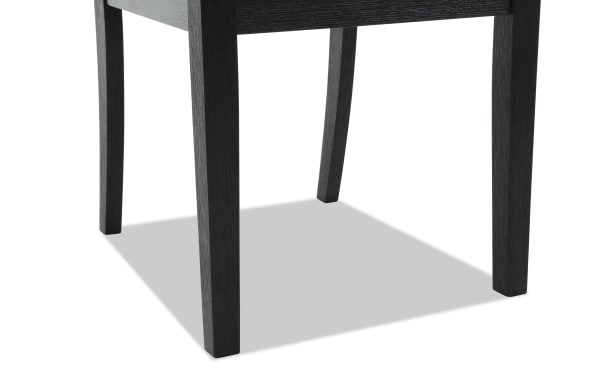 Black wooden chair legs with a smooth finish casting a shadow, highlighting sturdy construction and modern design.