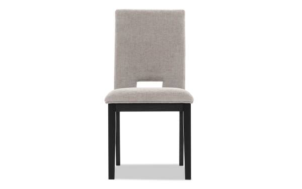 Upholstered dining chair with beige fabric seat and backrest, black wooden legs, and a modern cutout design on the lower backrest.