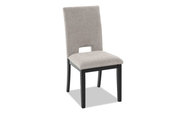 Upholstered dining chair with beige fabric seat and backrest, black wooden legs, and a modern cutout design on the lower backrest.