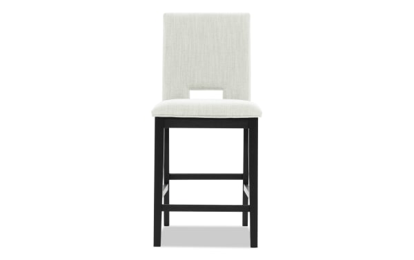 Upholstered dining chair with light gray fabric seat and backrest, black wooden legs, and a rectangular cutout in the backrest.