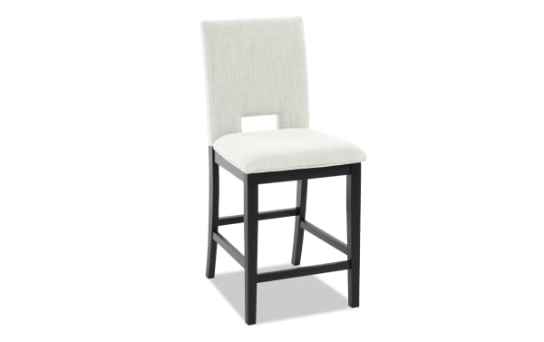 Bar stool with black wooden legs and a cushioned seat and backrest upholstered in light beige fabric, featuring a rectangular cutout in the backrest.