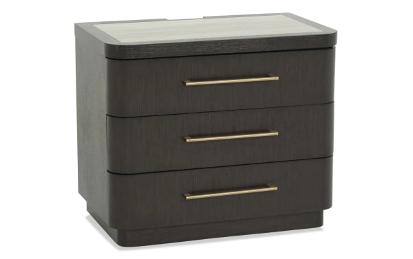Dark wood three-drawer nightstand with rounded edges, gold metal handles, and a light wood top panel, modern bedroom furniture.