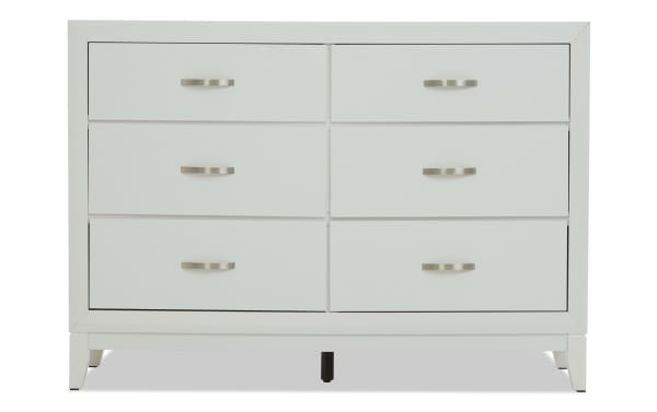 White wooden dresser with six drawers, brushed metal handles, and a modern, clean-lined design, ideal for bedroom storage.
