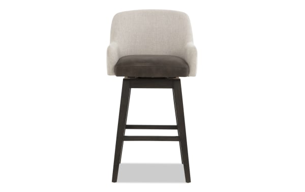 Swivel bar stool with beige fabric backrest, dark brown leather seat cushion, and dark wood tapered legs with footrest, modern style.