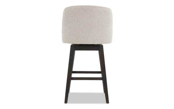 Upholstered bar stool with beige fabric seat and dark wood tapered legs, featuring a supportive backrest and footrest for comfortable seating.