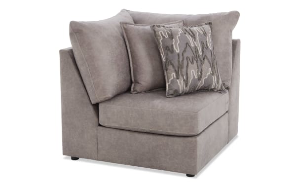 Gray fabric corner sofa chair with plush cushions and patterned throw pillow, modern sectional seating for living room.