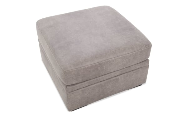 Square ottoman upholstered in light gray faux leather with cushioned top and stitched detailing, suitable for living room seating or footrest.