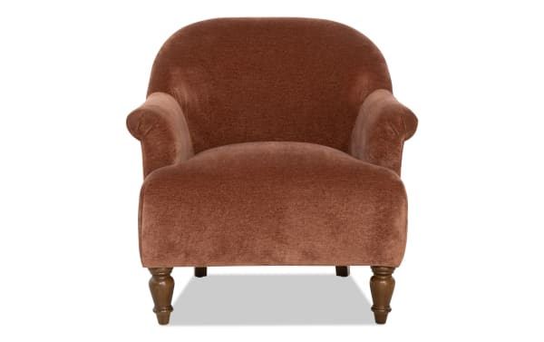 Brown velvet upholstered armchair with rounded back and rolled arms, featuring turned wooden legs in a classic style.