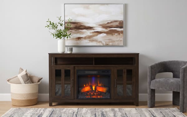 Dark wood electric fireplace TV stand with glass cabinet doors, realistic flame effect, and modern decor including a vase and abstract wall art.