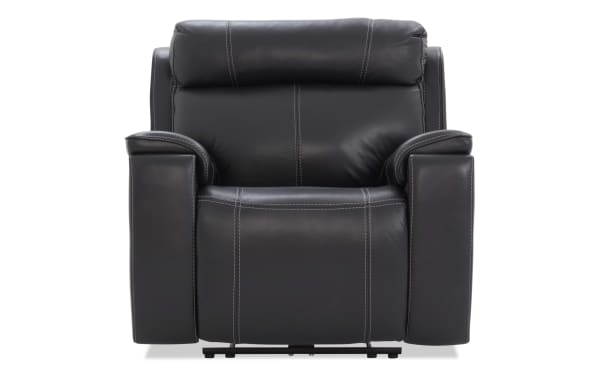 Black leather recliner chair with padded armrests, cushioned backrest, and visible white stitching, designed for comfort and modern living rooms.