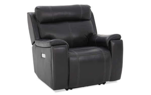 Black leather recliner chair with white stitching, padded armrests, high cushioned backrest, and built-in control panel on the side.