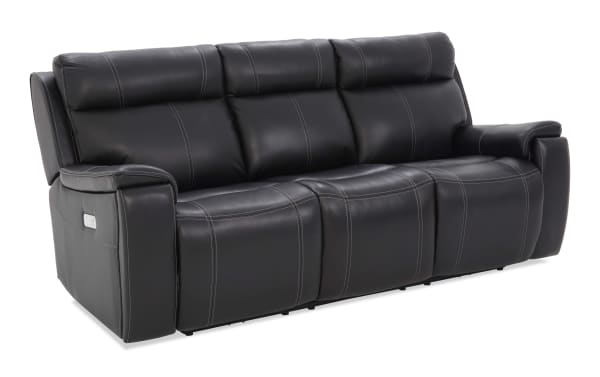 Black leather reclining sofa with three seats, visible stitching, padded armrests, and built-in control panel on the side.