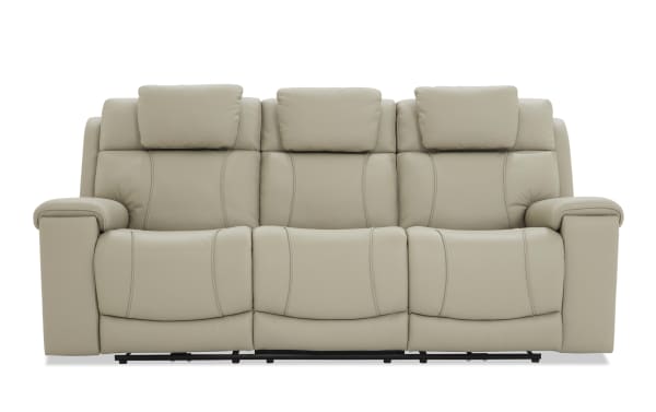 Beige leather reclining sofa with three seats, padded headrests, and cushioned armrests, designed for living room comfort and style.