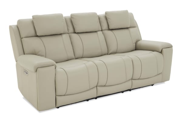 Beige leather three-seater reclining sofa with padded armrests and headrests, featuring a modern design and built-in control panel on the side.