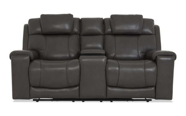 Dark gray leather reclining loveseat with padded armrests, high backrests, and a center console for storage and cup holders.