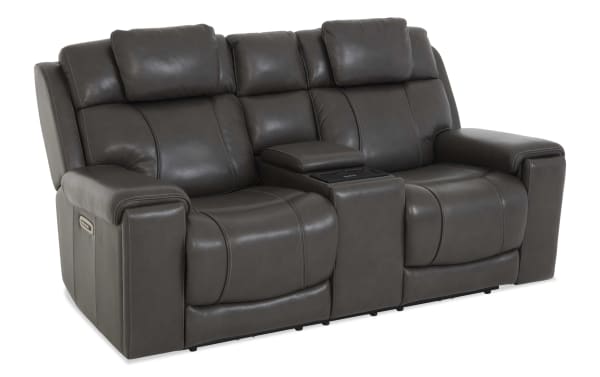Dark gray leather reclining loveseat with plush padded headrests, wide armrests, and a center console with cup holders, designed for living room comfort.