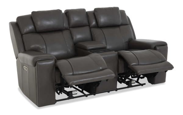 Dark gray leather reclining loveseat with plush cushioned backrests, padded armrests, and a center console with storage and cup holders, designed for comfort and relaxation.