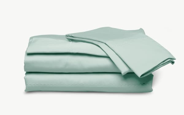 Soft, light green cotton bed sheet set with scalloped embroidery, neatly folded for bedroom linen or home decor use.
