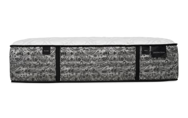 Mattress side view with gray and black paisley fabric, black piping, and white quilted top. Tags read "PLUSH," "FIRM," and "DISTINCTION."