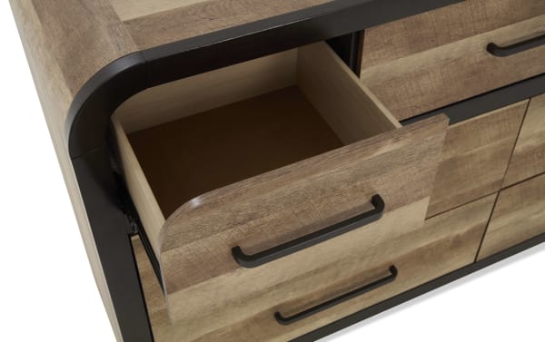 Wooden dresser drawer with a black metal handle, partially open, showing light wood interior and rustic wood grain finish.