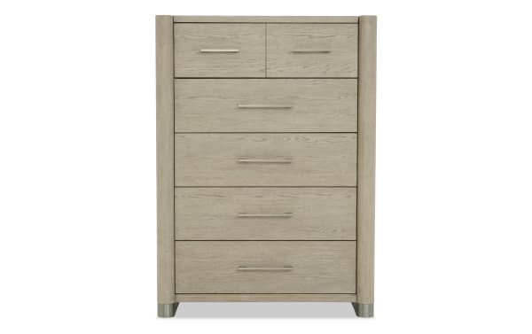 Tall light oak wood dresser with five drawers, featuring modern metal handles and rounded vertical side panels, ideal for bedroom storage.