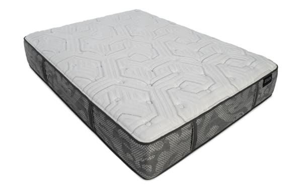 Mattress with a quilted white top featuring geometric patterns and a gray fabric side with a textured zigzag design, labeled "ZEUS."