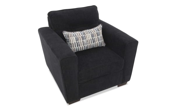 Black upholstered armchair with wide padded arms, a cushioned backrest, and a patterned lumbar pillow, ideal for modern living rooms.