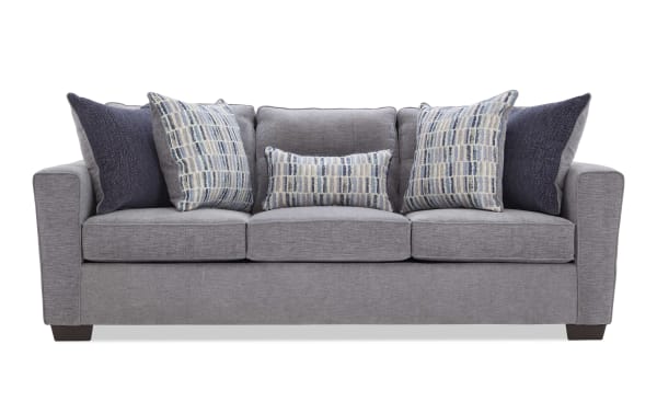Modern gray fabric sofa with three seat cushions, dark wooden legs, and six decorative pillows in blue and patterned designs, ideal for living room seating.