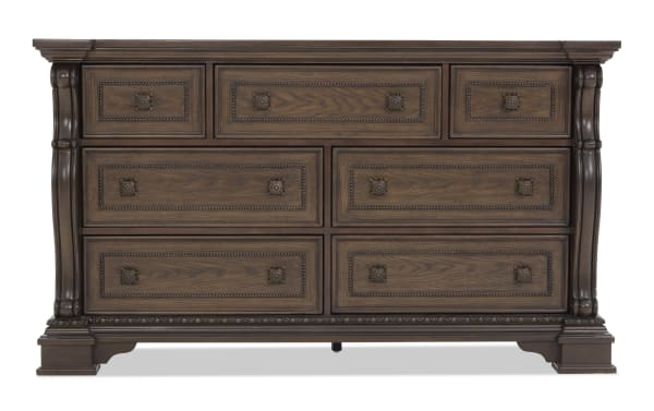 Traditional wooden dresser with dark brown finish, ornate carved details, and nine drawers featuring decorative metal handles, ideal for bedroom storage.