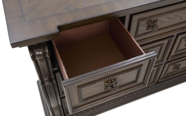 Dark wood office desk drawer open, showcasing detailed carved panel design and antique brass handle, highlighting classic craftsmanship and storage function.