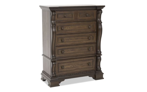 Dark brown wooden chest of drawers with ornate carved details, six drawers with decorative handles, classic traditional style furniture.
