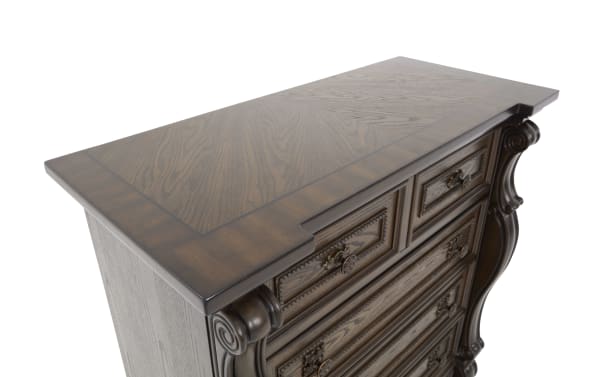 Dark wood dresser with ornate carved details, multiple drawers with decorative metal handles, and a polished finish on top panel.